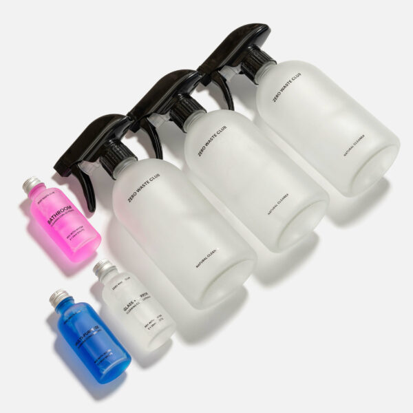 Three glass bottles with spray, screw on, and pump tops next two cleaning concentrate bottles